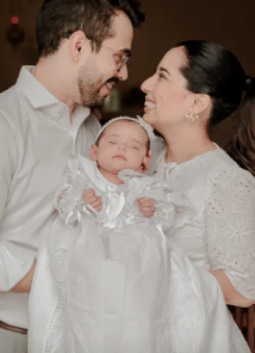 Helô e o marido segurando a filha recém-nascida no batizado