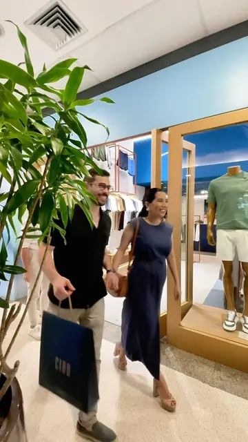 Helô e o marido caminhando num shopping com sacolas de compras